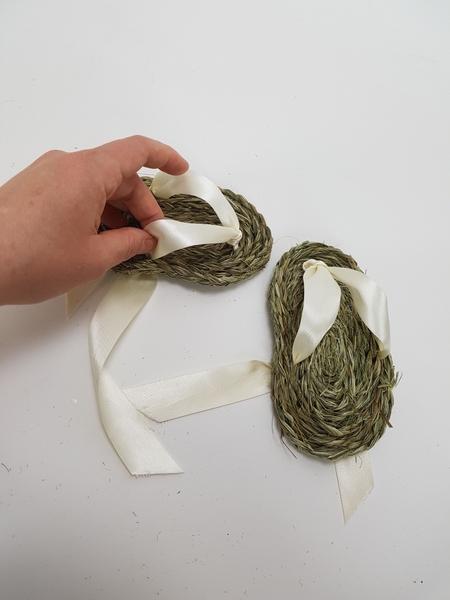 Fold the ribbon over to the front of the sandal, over the bridge of the foot. Fold the ribbon over to the front of the sandal, over the bridge of the foot.