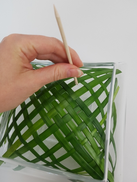 Spread out the woven blades of grass to fill the opening of the container. Spread out the woven blades of grass to fill the opening of the container.