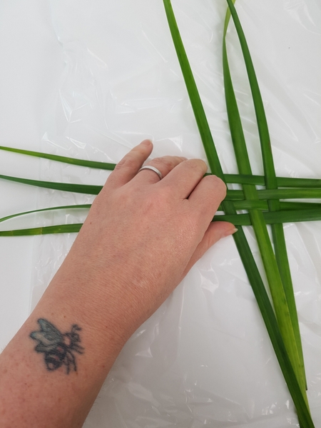 Weave a few blades of lily grass into a basic weaving pattern Weave a few blades of lily grass into a basic weaving pattern