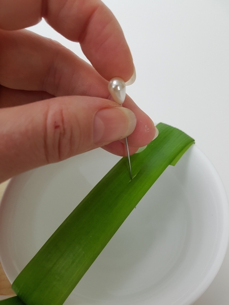 Make a tiny slit in the blade of grass with a pin. Make a tiny slit in the blade of grass with a pin.