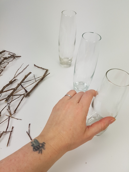 Place three bud vases on a working surface Place three bud vases on a working surface