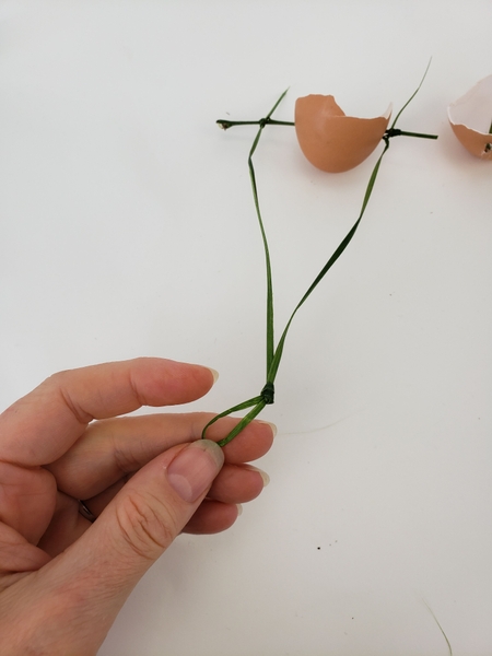 Make a knot in the middle of the ripped grass to give it a secure way to hang from the design Make a knot in the middle of the ripped grass to give it a secure way to hang from the design