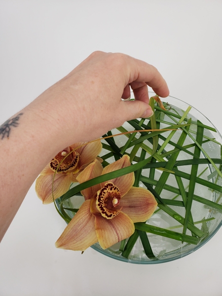 Add a few mature grass curls to mirror the sun colour of the orchids Add a few mature grass curls to mirror the sun colour of the orchids