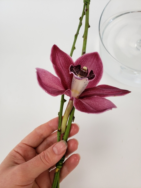 Slip the flower between the two twigs so that it is wedged into place Slip the flower between the two twigs so that it is wedged into place