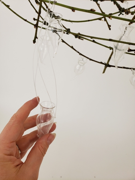 Wire or hang tiny vases to keep the fresh flowers hydrated. Wire or hang tiny vases to keep the fresh flowers hydrated.