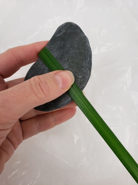 Wrap a blade of grass around the rock like a band and glue Wrap a blade of grass around the rock like a band and glue