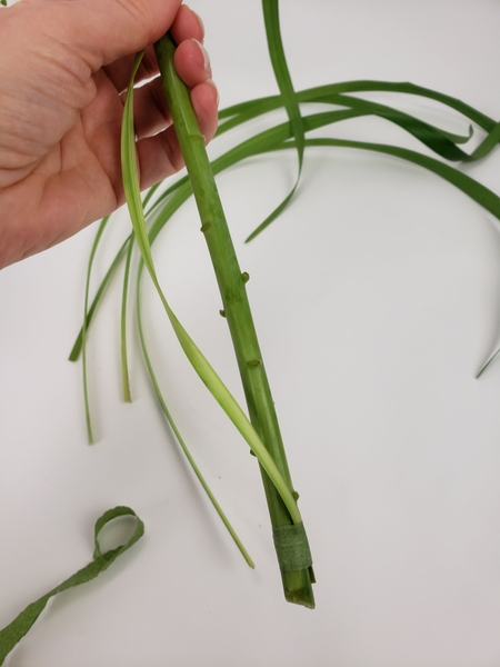 Bind a blade of grass to the flower stem with florist tape Bind a blade of grass to the flower stem with florist tape