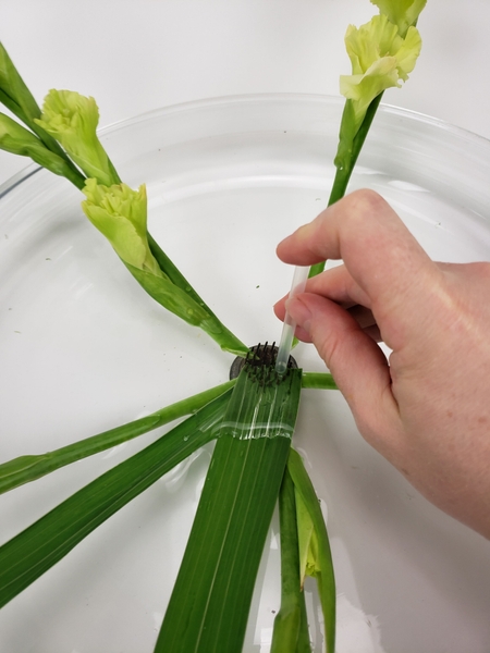 Gently press the leaves down into the Kenzan using a drinking straw Gently press the leaves down into the Kenzan using a drinking straw