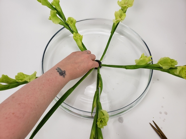 Place the stem with the foliage in between the flower stems Place the stem with the foliage in between the flower stems
