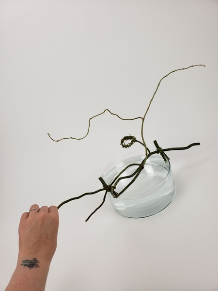 Twist the willow branch so that the wreath is positioned over the water Twist the willow branch so that the wreath is positioned over the water