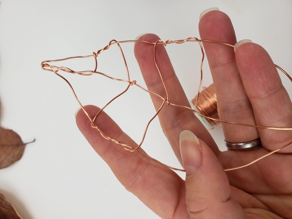 Twist the wire around the sides of the leaf and work your way towards the middle at a slight angle Twist the wire around the sides of the leaf and work your way towards the middle at a slight angle