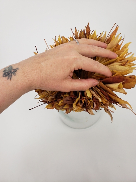 Fan out the top folded autumn leaves to fold back over the edge of the container Fan out the top folded autumn leaves to fold back over the edge of the container