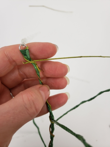 Press the next weaving stem through a gap in the first stem and again wind it around the wire Press the next weaving stem through a gap in the first stem and again wind it around the wire