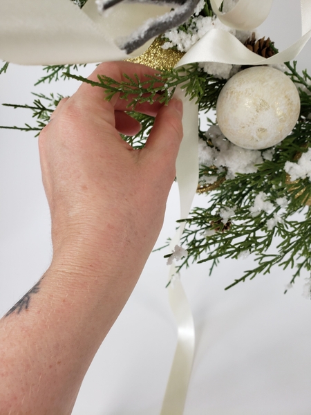 The longest tail of the ribbon is tucked behind a branch to keep it neatly in place.