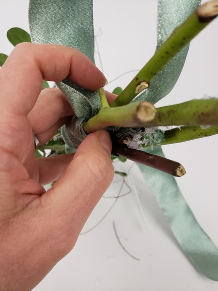 The short tail from the looped ribbon goes back into the covered stems The short tail from the looped ribbon goes back into the covered stems
