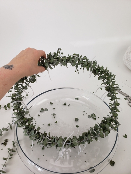 Build up the wreath shape by stacking stems around and around the design Build up the wreath shape by stacking stems around and around the design