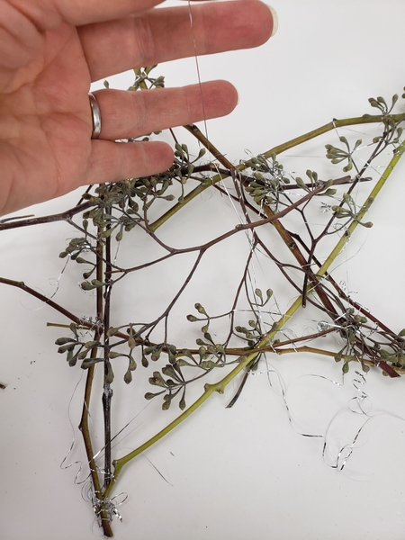 Tie the stems and seedpods with tinsel and curl the tinsel ends Tie the stems and seedpods with tinsel and curl the tinsel ends