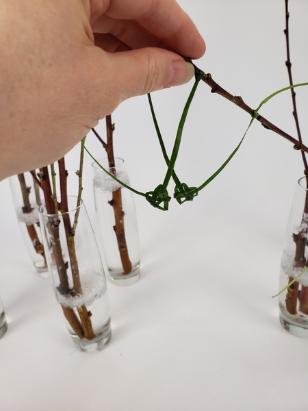 Secure the grass by knotting the end to the branch Secure the grass by knotting the end to the branch