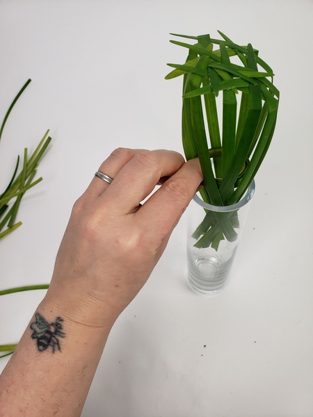 Slip the grass into the vase so that it is between the grass circle and the glass Slip the grass into the vase so that it is between the grass circle and the glass