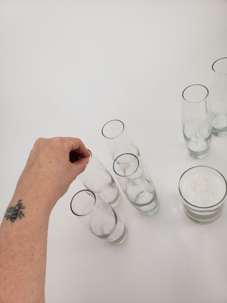 Sprinkle a tiny bit of artificial snow in six bud vases Sprinkle a tiny bit of artificial snow in six bud vases