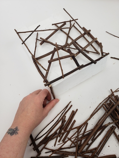 Start to glue twigs to the bottom edge of the shape Start to glue twigs to the bottom edge of the shape