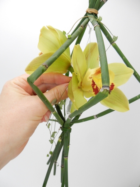 Place the flowers and the vine in the vase Place the flowers and the vine in the vase