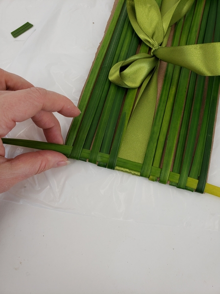 Move the first woven strand right to the edge of the cardboard. Move the first woven strand right to the edge of the cardboard.