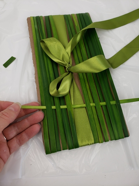Weave the first strand of grass into the bands. Weave the first strand of grass into the bands.