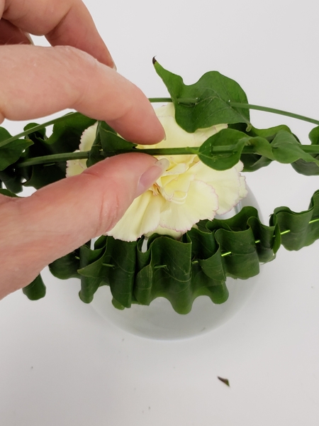 Add a few ruffled leaves skewered onto twigs to arch over the design Add a few ruffled leaves skewered onto twigs to arch over the design
