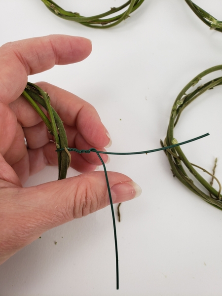 Twist a wire around the first wreath. Twist a wire around the first wreath.
