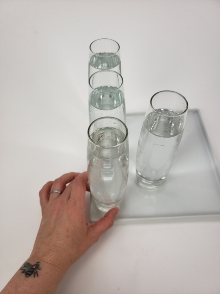 Place water filled bud vases of a display tray Place water filled bud vases of a display tray