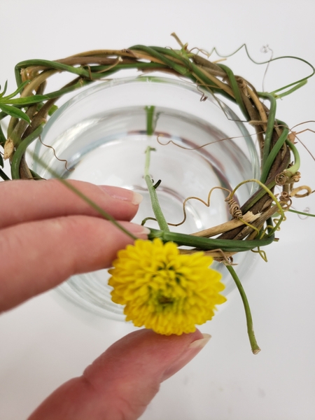 Slip a flower through the wreath so that the stem is at an angle Slip a flower through the wreath so that the stem is at an angle