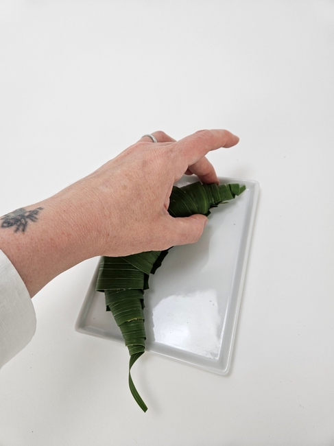 Roll gladiolus leaves into tubes to craft a raft for a toad lily stem
